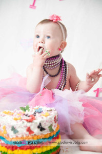 bambina con tutù e collana di perle mangia la torta del suo primo compleanno