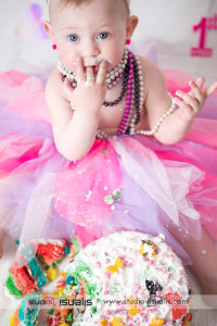 bambina di un anno con tutù e collane di perle mangia la torta del suo primo compleanno