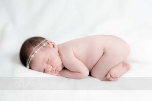 neonata addormentata a pancia in giú su sfondo bianco