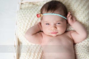neonata con occhi aperti e fiore in testa