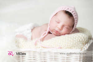 neonata addormentata con cappellino rosa su sfondo bianco